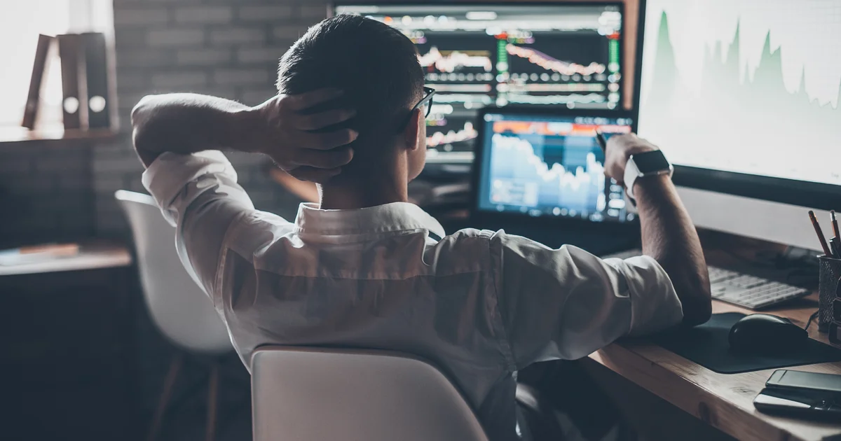 Un inversor se recuesta en su silla ante varias pantallas con gráficos de bolsa, mientras Anthropic prepara su salida a Wall Street