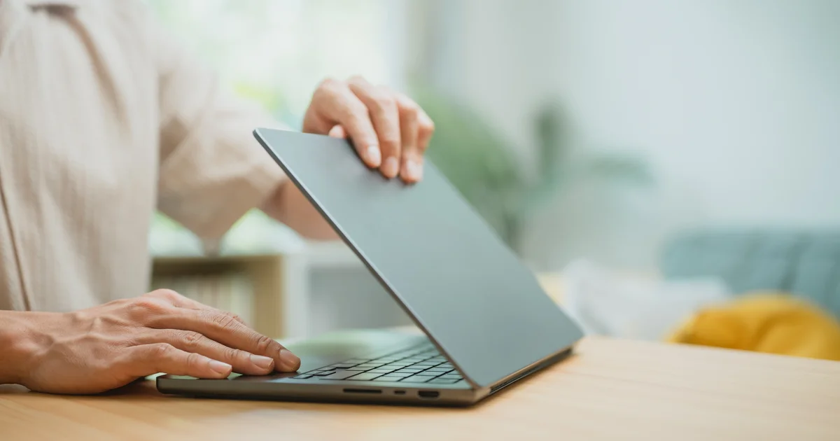 Una persona abre un portátil sobre una mesa de casa, como tantos usuarios españoles que ya ven anuncios en el ChatGPT gratuito