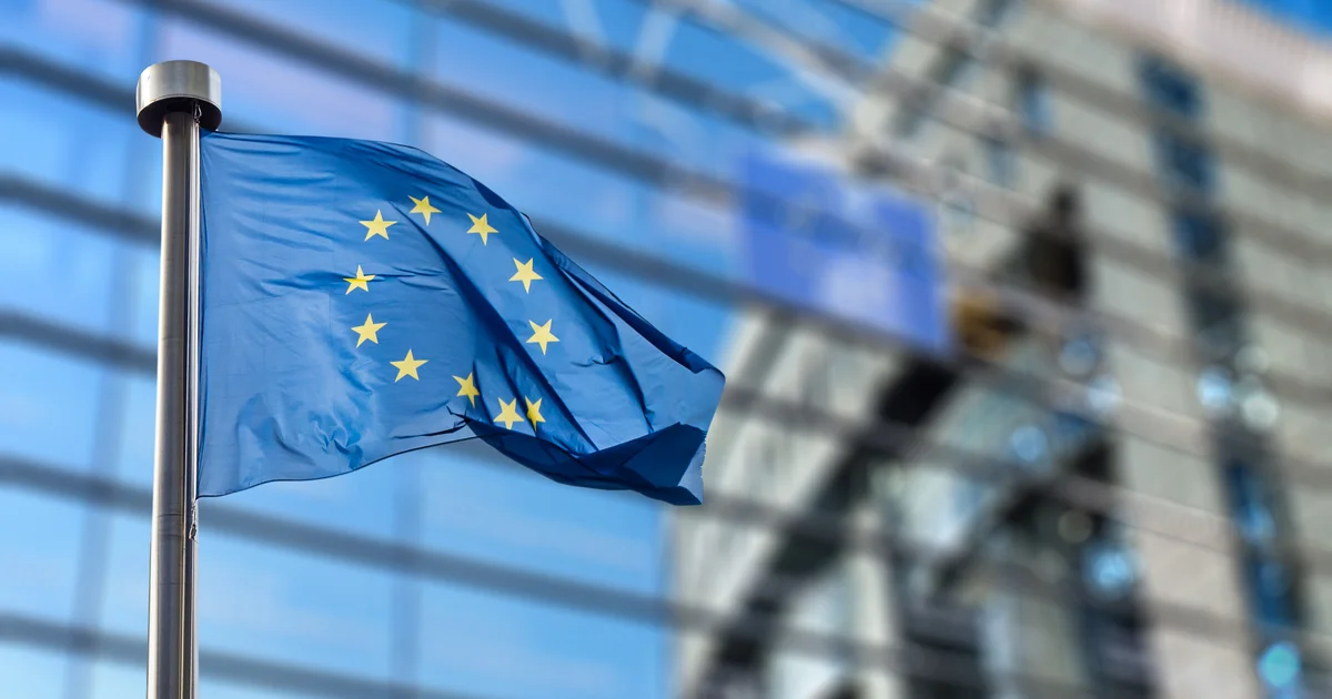 Bandera de la Unión Europea ondeando ante un edificio acristalado