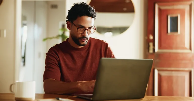 Un hombre con gafas trabaja con un portátil en la mesa de casa, el tipo de equipo propio donde se puede ejecutar un modelo descargable como Muse Spark Open sin mandar datos a la nube