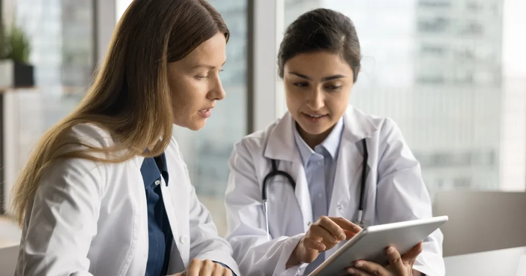 Dos médicas revisan datos de un paciente en una tableta, el tipo de acceso a historiales que dejaba al descubierto el fallo de MyChart