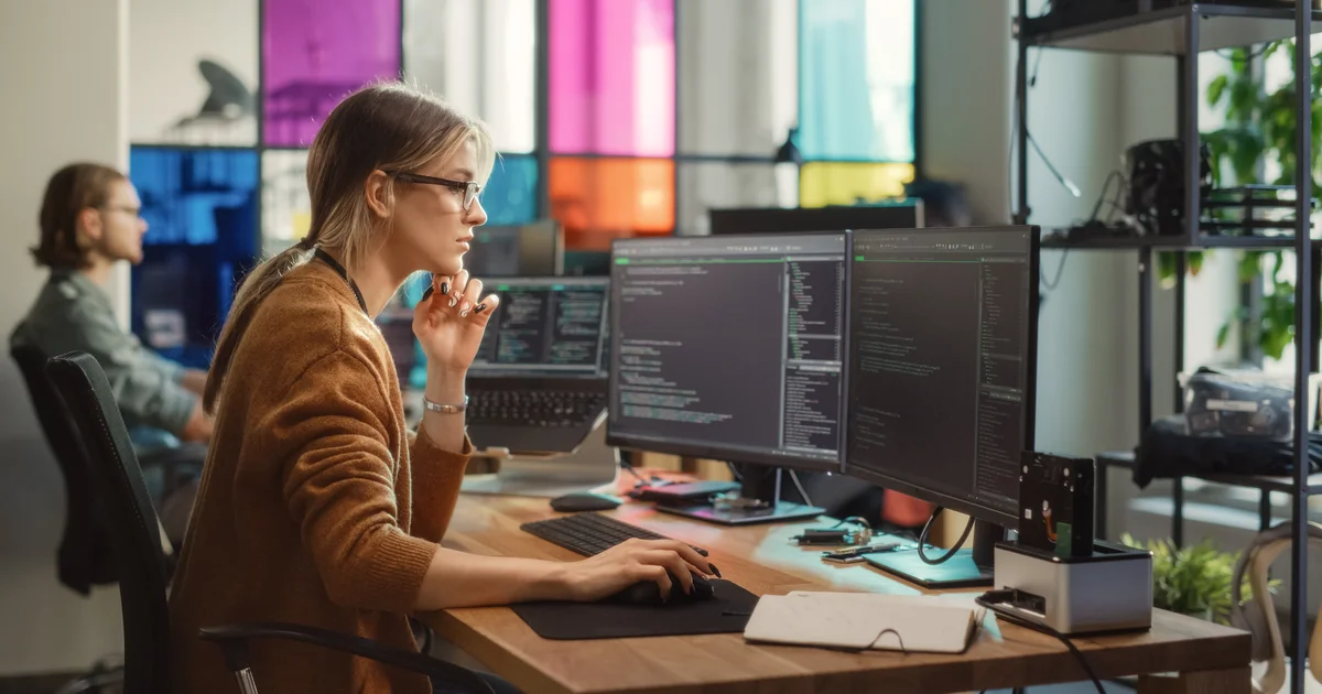 Una ingeniera de software estudia código en dos monitores, mientras los hospitales que usan Epic corren a instalar parches de seguridad