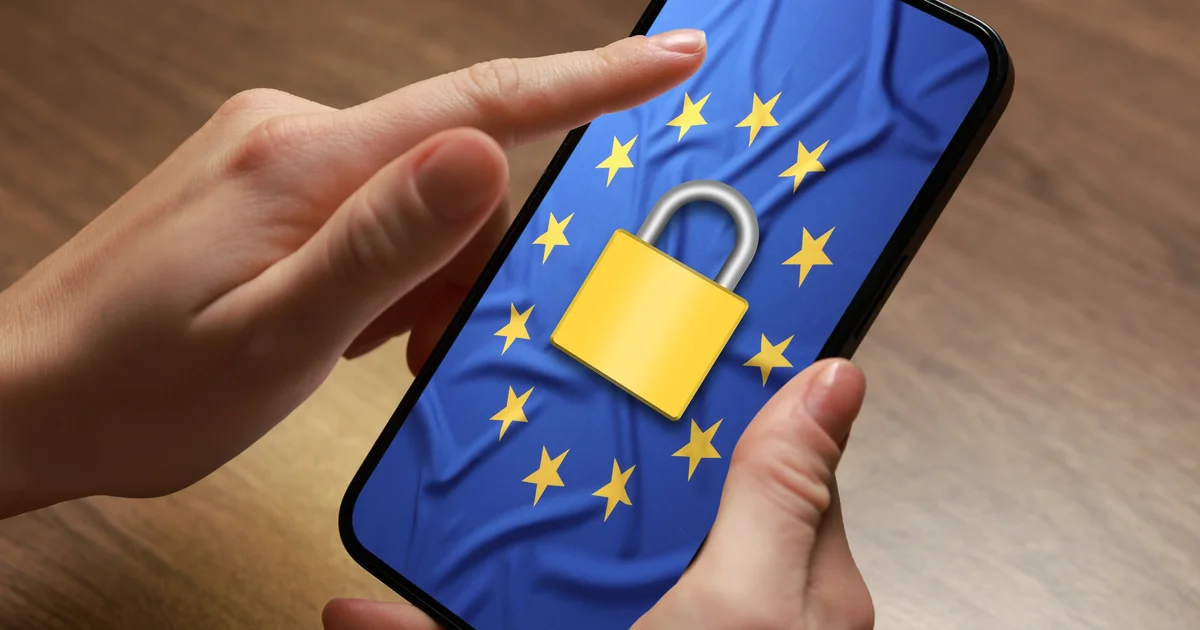 Manos sujetando un móvil que muestra la bandera de la Unión Europea con un candado, para ilustrar los requisitos que esta norma deja para otras normas, como la ciberseguridad