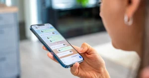 Una mujer mira un chat de WhatsApp con notas de voz desde su móvil, para ilustrar la noticia sobre las órdenes ocultas para el chatbot de soporte de WhatsApp